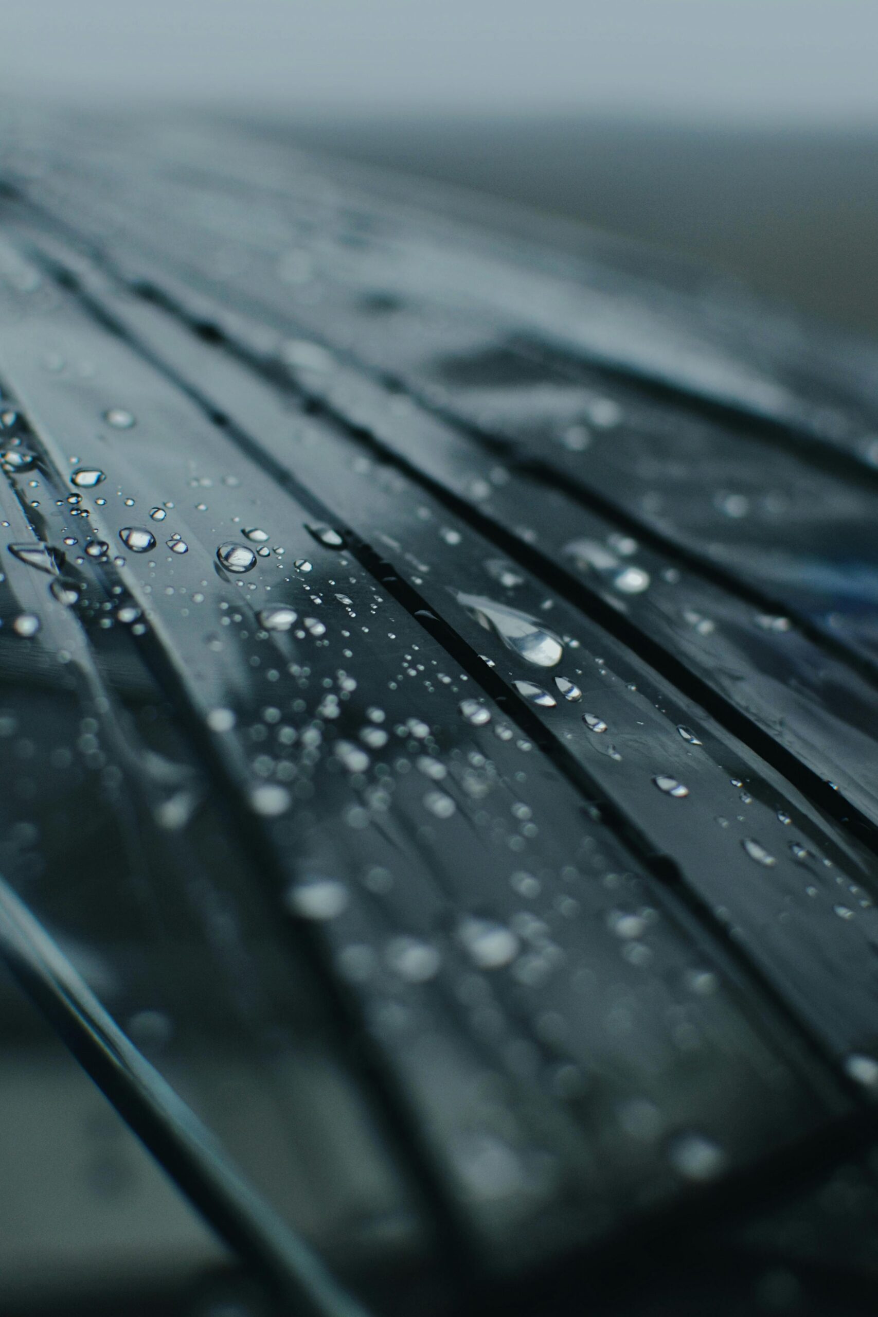 Detailed view of raindrops on a glass surface with a moody atmosphere.